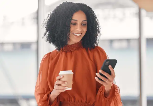 Een jonge vrouw die aan haar mobiele telefoon werkt en blij is met haar werk