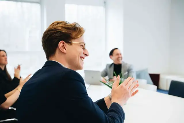 Een glimlachende medewerker van Sander in een vergadering